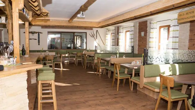 Hopfenstub’n mit Holzbalken, Theke und grün gepolsterten Bänken